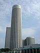 Ground-level view of a tall, white cylindrical tower and a shorter cuboidal building