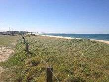 A stretch of beach and sand dunes; sea is to the right of the picture