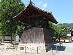 A bronze bell in a wooden belfry.