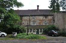 A wide, two-storey stone house with remains of a much older building