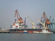 berthed freighter with two smaller ships moored next to it